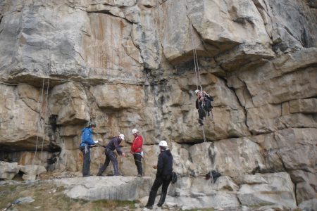 Photo of 4 climbers at the base of a rock climb and Logo of Wessex Mountaineering