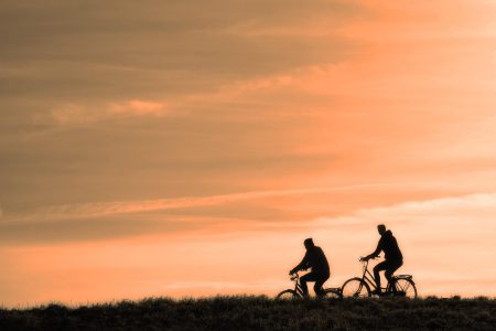 Logo and photograph of two cyclists with a sunset behind them
