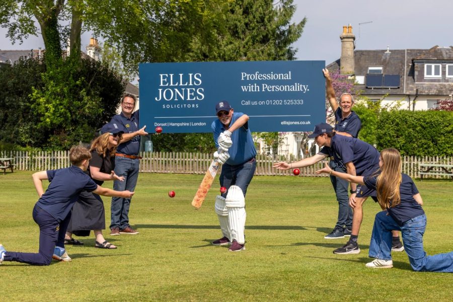 Club logo and posed photo of players surrounding a batsman
