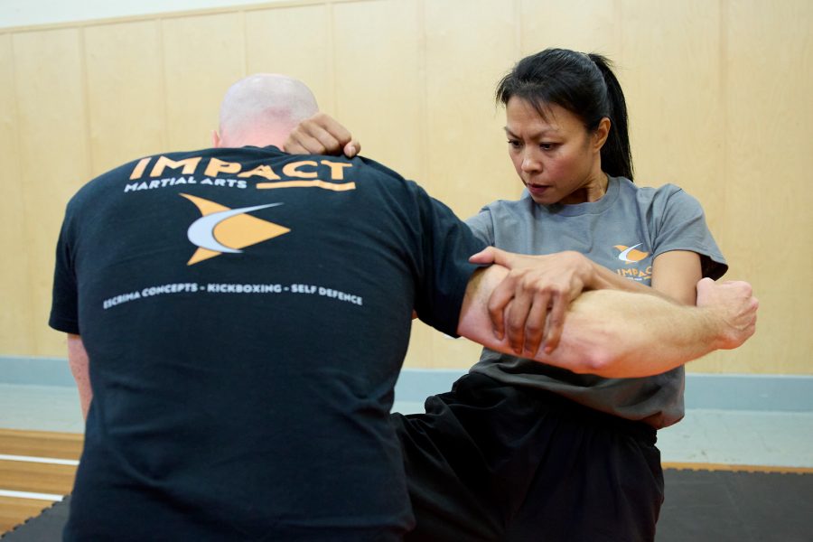 Impact Martial Arts logo and photograph of a man and a woman in martial arts combat