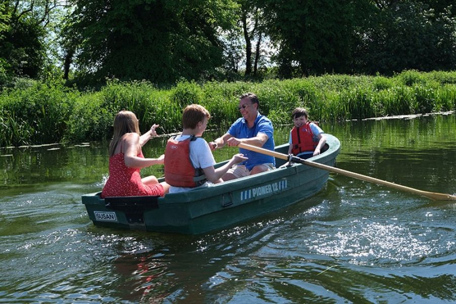 Photograph of 4 people rowing a boat on the River Stour, on a sunny day