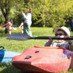 Young child sitting in a kayak on the grass at the Sports and Active Leisure Festival