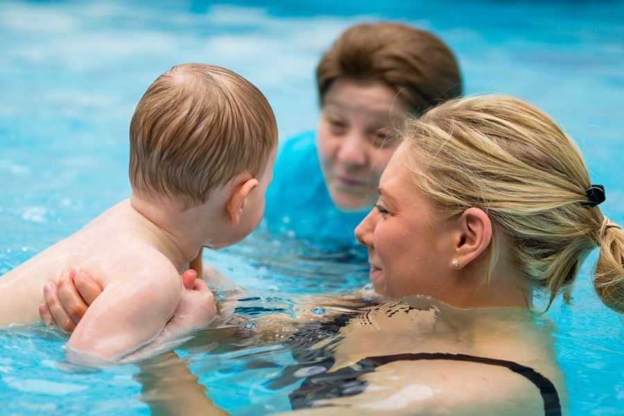 Photograph of 2 adults with a young child in a swimming pool plus Puddle Ducks logo