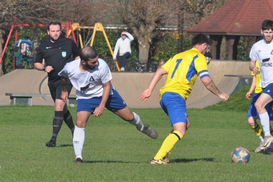 action photograph of football match with 3 players and referee and Club Logo